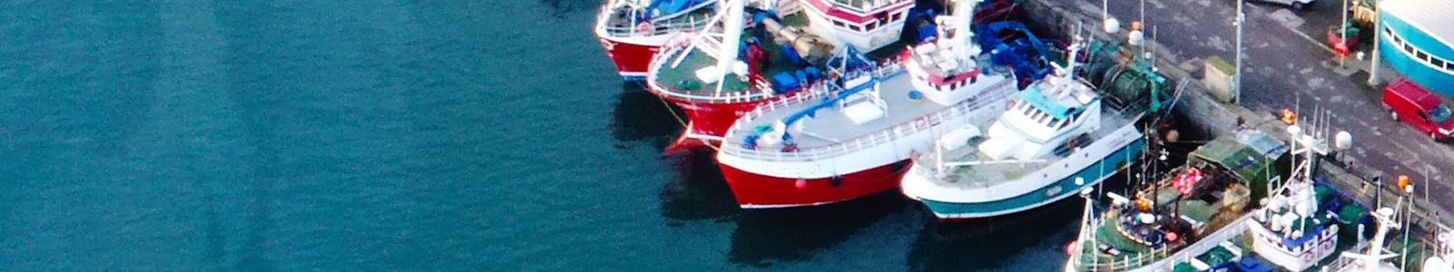 multiple fishing trawlers berthed at sea port pier